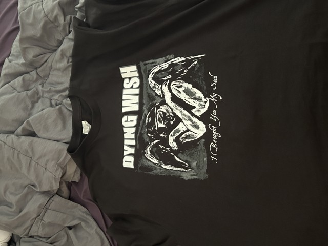 Photo of a black T Shirt with a sketchy drawing of an angel with the text 'Dying Wish' in white.